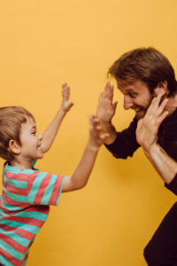 Dad high fiving child, teaching and guiding positive behavior rather than punishing.